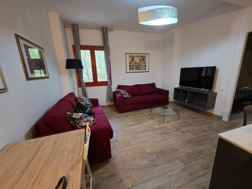 a living room with a red couch and a flat screen tv at La Tana del Capriolo in Prati di Tivo