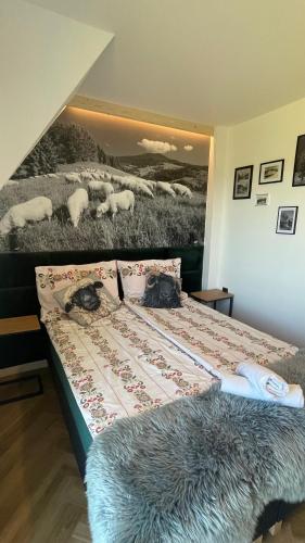 a bed in a room with a painting of sheep at Apartament u Jagi Sądelska 119f in Murzasichle