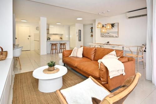 a living room with a couch and a kitchen at Luxe Coastal Escape, Sunny Coast in Maroochydore