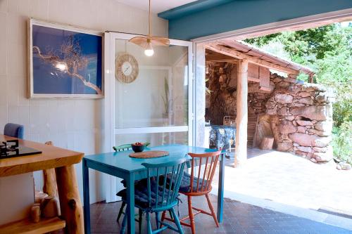 a blue table and chairs in a kitchen with a stone wall at O Quinteiro de Elvira in Moaña