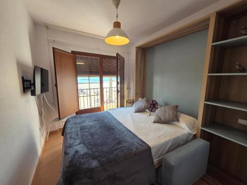 sypialnia z łóżkiem i dużym oknem w obiekcie AR1B, Acogedor estudio a pie de playa w mieście Villajoyosa