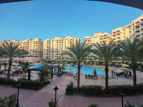 einem großen Pool mit Palmen vor einem großen Gebäude in der Unterkunft منتجع اكوا ڤيو الساحل الشمالي in El Qasaba esh Sharqīya