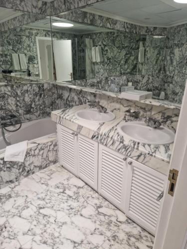 a marble bathroom with two sinks and a tub at Anfi Beach in Mogán