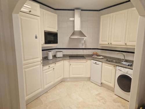 a kitchen with white cabinets and a washer and dryer at Anfi Beach in Mogán