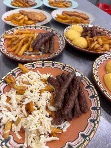 a table full of plates of food with sausages and fries at Cob Village in Berca