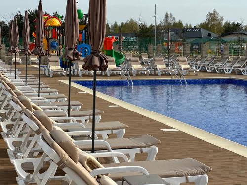 a swimming pool with lounge chairs and umbrellas at Grand Łeba - Adults Only (13+) in Łeba