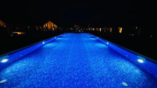 a blue pool of water at night with lights at Grand Łeba - Adults Only (13+) in Łeba