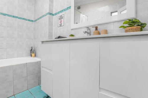 a white bathroom with a sink and a mirror at 2 Bedroom House Surry Hills Good for 6 Guests in Sydney