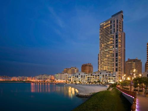 un grande edificio accanto a un corpo idrico di Hilton Doha The Pearl a Doha