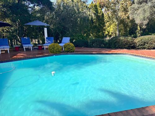 a large blue swimming pool with chairs and umbrellas at Footprints Self Catering Indoor Heated Pool and Fireplaces in Lanseria
