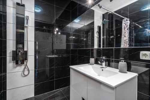 a black tiled bathroom with a sink and a shower at Casa Terrace Carvoeiro in Carvoeiro