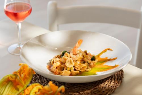 a white bowl of food and a glass of wine at Borgo Mulino a Vento - Resort in Uggiano la Chiesa