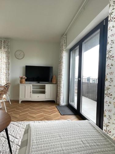 a living room with a tv and a large window at Apartament Aleja Poetów in Chojnice