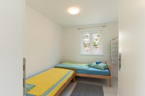 deux lits dans une petite pièce avec une fenêtre dans l'établissement Sunset, à Kustići