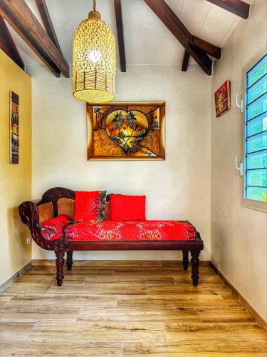 a red couch sitting in a room with a chandelier at Ti Ben - Jacuzzi Privatif Jardin Tropical - Le Robert in Le Robert