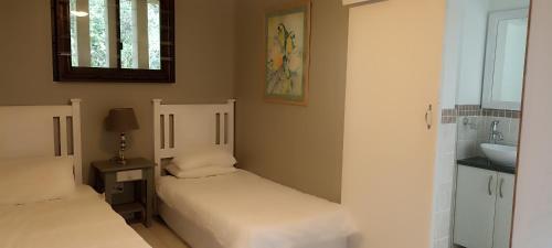 1 dormitorio con 2 camas, lavabo y espejo en Beach & Golf Escape, en Southbroom