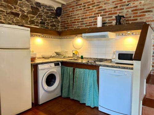 a kitchen with a washing machine and a microwave at La Casona del Cura 3, CALÉNDULA in Pravia