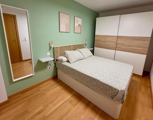 ein kleines Schlafzimmer mit einem Bett und einem Spiegel in der Unterkunft Apartamento Blesino in Saragossa