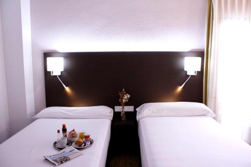 two beds in a hotel room with a tray of food at Pacoche Murcia in Murcia