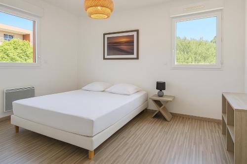 une chambre blanche avec un lit et deux fenêtres dans l'établissement APPARTEMENT T3 65 m2 CENTRE VILLE, à Porto-Vecchio