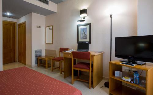 a hotel room with a television and a desk with chairs at Pacoche Murcia in Murcia