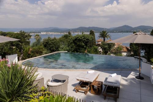 a swimming pool with umbrellas and a view of the water at Tinah Saint-Tropez in Saint-Tropez