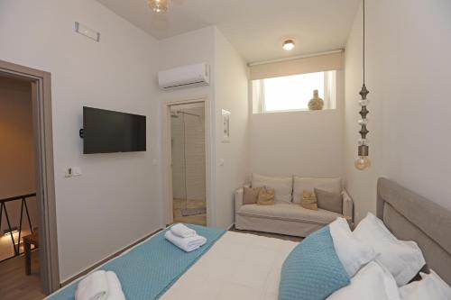 a bedroom with a bed and a tv and a couch at Casa di Lou in Ermoupoli