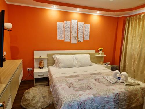 a bedroom with a bed with an orange wall at Central Apartment in Petroşani