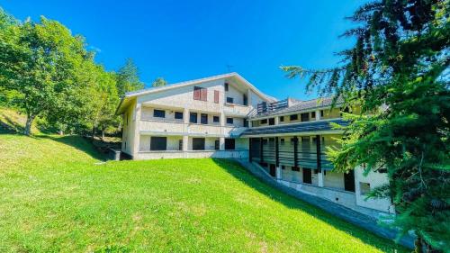 a large house on a hill with green grass at Appartamento La Chapelle Rocciamelone - Affitti Brevi Italia in Sauze dʼOulx
