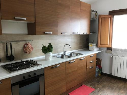 a kitchen with wooden cabinets and a sink and a stove at Stazzo Gallurese con vista sul golfo di Olbia in Pittulongu
