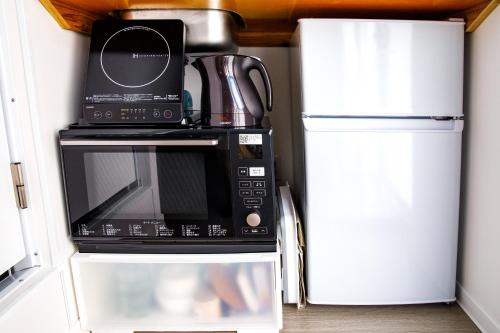 a microwave oven with a coffee pot on top of it at 最大18名OK 南城市 百名の大型貸別荘 BBQ ビーチ近くでグループ滞在に最適 Seaside House Ichika in Nanjo