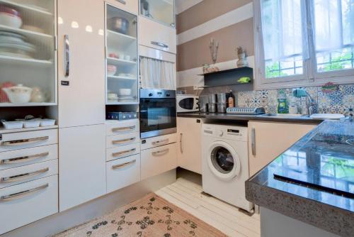 une cuisine avec des armoires blanches et une laveuse et une sécheuse dans l'établissement La Maison B - L'auberge autonome au charme vintage, à Bergerac