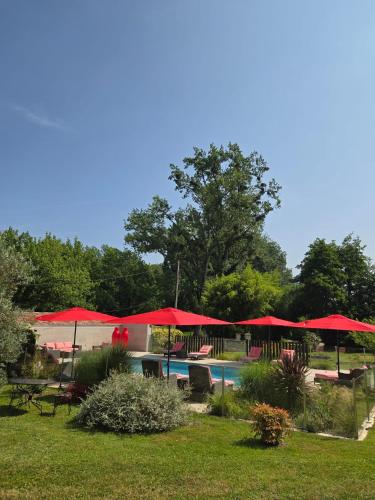 a pool with red umbrellas and tables and chairs at Château de Courtebotte in Saint-Jean-de-Blaignac