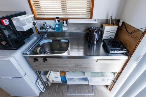 a small kitchen with a sink and a microwave at 最大18名OK 南城市 百名の大型貸別荘 BBQ ビーチ近くでグループ滞在に最適 Seaside House Ichika in Nanjo