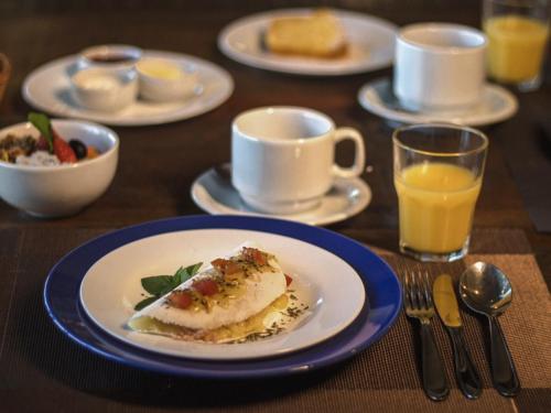 a table with a plate of food and a cup of orange juice at Ilha de Toque Toque Eco Hotel in São Sebastião