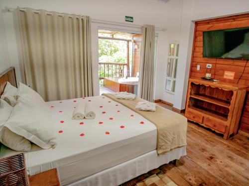 a bedroom with a large white bed with red hearts on it at Ilha de Toque Toque Eco Hotel in São Sebastião
