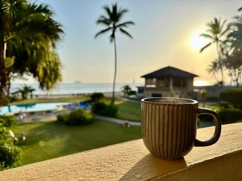 a coffee cup sitting on the ledge of a balcony at Agualina Kite Hotel Oceanfront Apartments in Cabarete