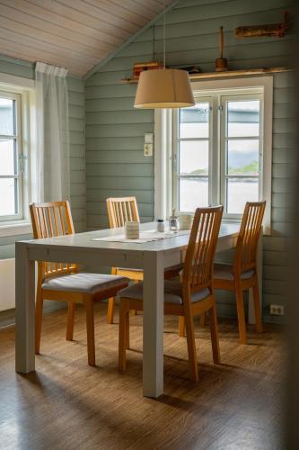 a dining room with a table and chairs and windows at Eliassen Rorbuer in Reine