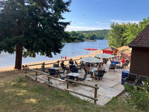 a group of people sitting on a wooden deck next to a lake at Camp Les Deux in Jouillat