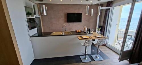 a kitchen with a sink and a counter with a table at T2 2-4 pers-Balcon-Magnifique Vue Mer et Baie des Sables d'Olonne in Les Sables-dʼOlonne