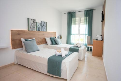 a bedroom with two beds and two ottomans at Hotel Caravaca Resort in Caravaca de la Cruz