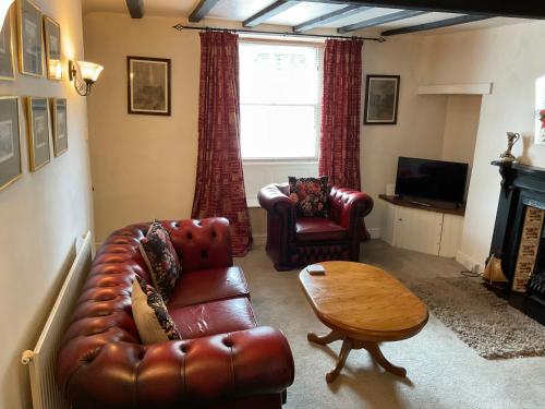 a living room with a leather couch and a table at Lark Cottage in Pickering