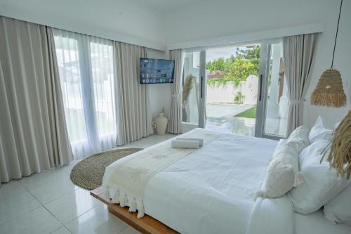 - une grande chambre blanche avec un grand lit et des fenêtres dans l'établissement Villa Nair NEW stylish 3BR Canggu with large pool, projector & green field view, à Canggu