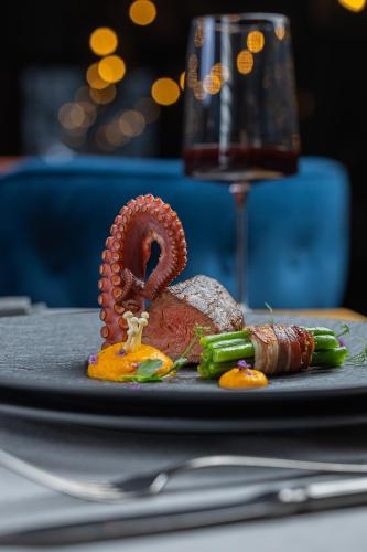 a plate of food on a table with a glass of wine at Kashmir Wellness & SPA Hotel Adults Only in Velingrad