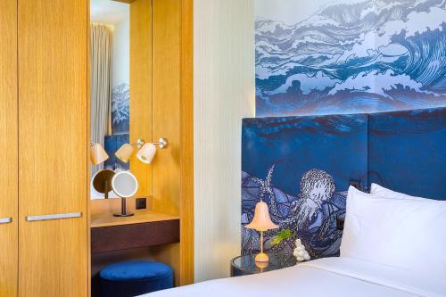 a bedroom with a bed with a painting on the wall at Kimpton BEM Budapest by IHG in Budapest