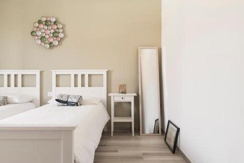 a white bedroom with two beds and a mirror at Casa Ferrant in Faloppio
