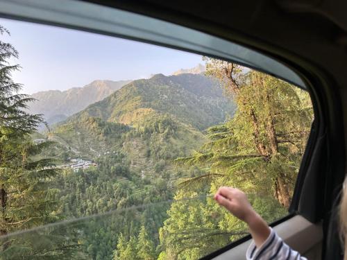 a person looking out of a window at a mountain view at Tranquil trails home stay naddi in Dharamshala