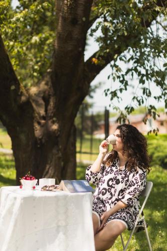a woman sitting at a table drinking from a cup at Casa Ferrant in Faloppio