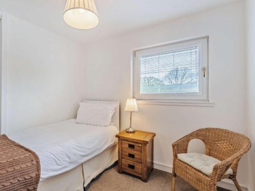 a bedroom with a bed and a chair and a window at 4 Bed in The Cairngorms 46162 in Tomintoul