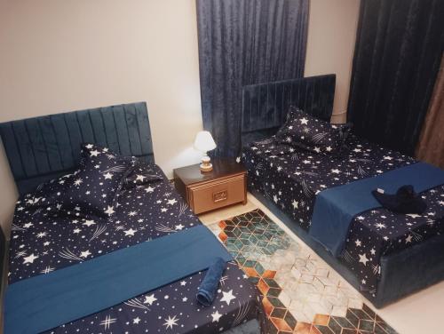 a bedroom with two beds and a table with a lamp at Time Off in Alexandria